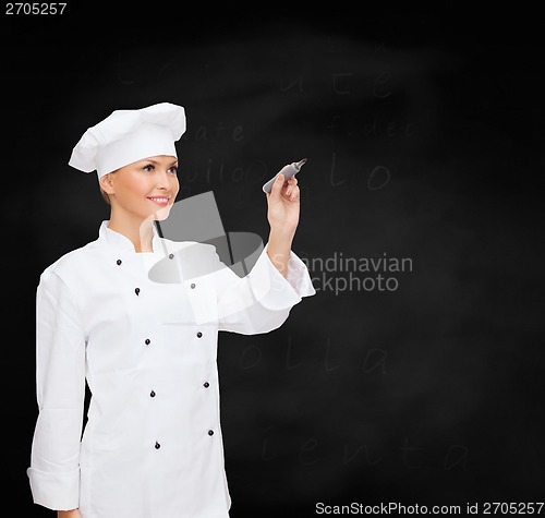 Image of smiling female chef writing something on air