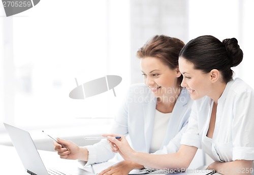 Image of smiling businesswomen working at laptop in office