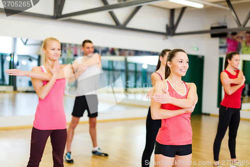 Image of group of smiling people stretching in the gym