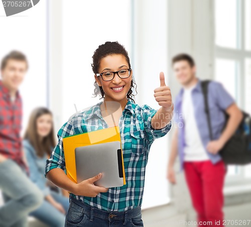 Image of student in eyeglasses with folders and tablet pc