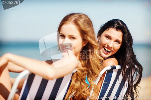 Image of girls sunbathing on the beach chairs