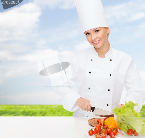 Image of smiling female chef chopping vagetables