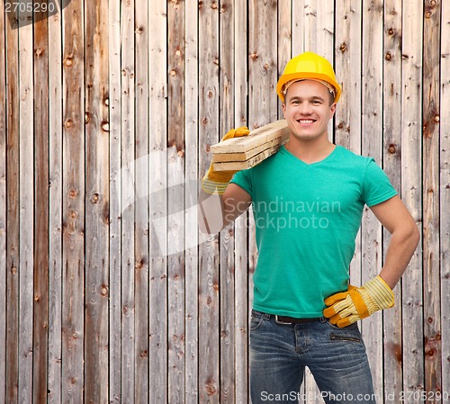 Image of smiling manual worker in helmet with wooden boards