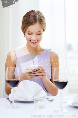 Image of smiling woman with smartphone at resturant