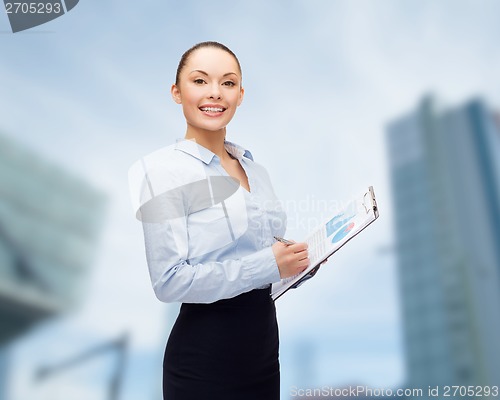 Image of young smiling businesswoman with clipboard and pen
