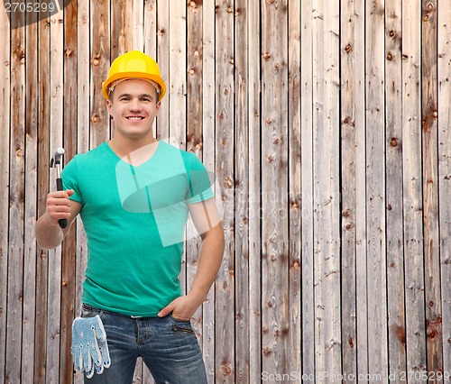 Image of smiling manual worker in helmet with hammer