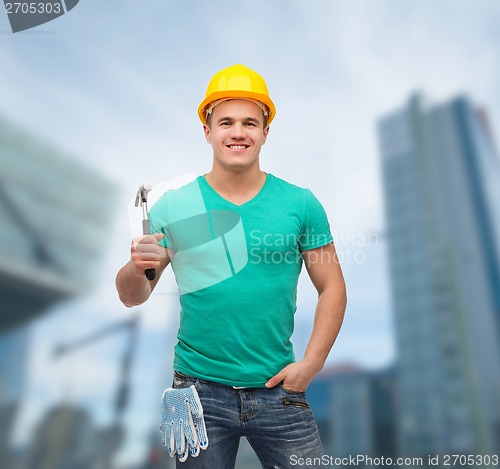 Image of smiling manual worker in helmet with hammer