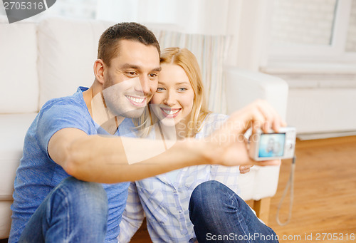 Image of smiling couple taking picture with digital camera