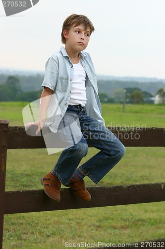 Image of Country boy sitting on a fence