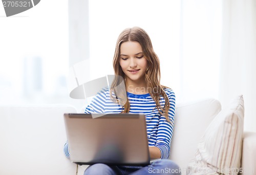 Image of smiling teenage girl with laptop computer at home