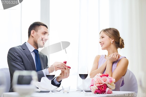 Image of man proposing to his girlfriend at restaurant