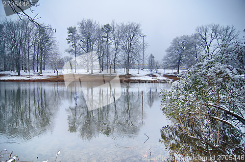 Image of tree line reflections in lake during winter snow storm