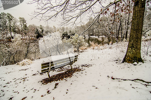 Image of park bench in the snow covered park overlooking lake