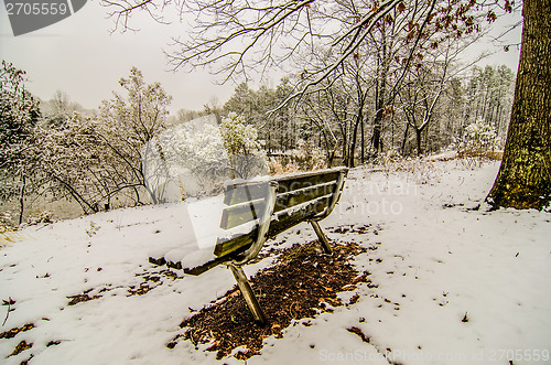 Image of park bench in the snow covered park overlooking lake