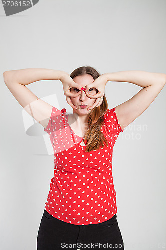 Image of Attractive woman looking through finger goggles