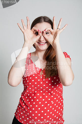 Image of Smiling attractive woman looking through finger goggles