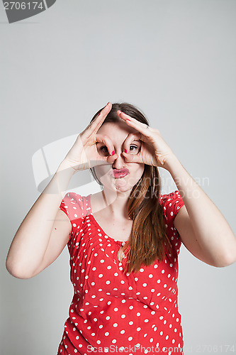 Image of Attractive woman looking through finger goggles
