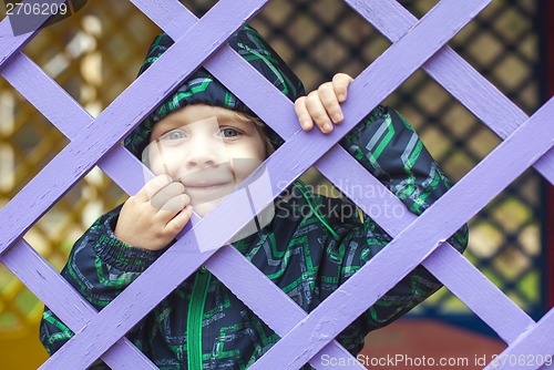 Image of little baby boy  looking through blue fence