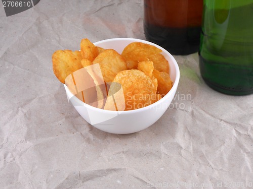 Image of Beer bottle and potato chips on white plate