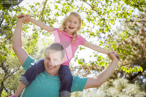 Image of Cute Young Girl Rides Piggyback On Her Dads Shoulders