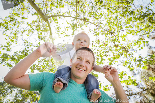 Image of Cute Young Boy Rides Piggyback On His Dads Shoulders