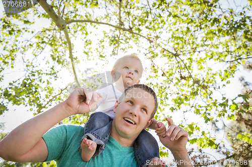 Image of Cute Young Boy Rides Piggyback On His Dads Shoulders