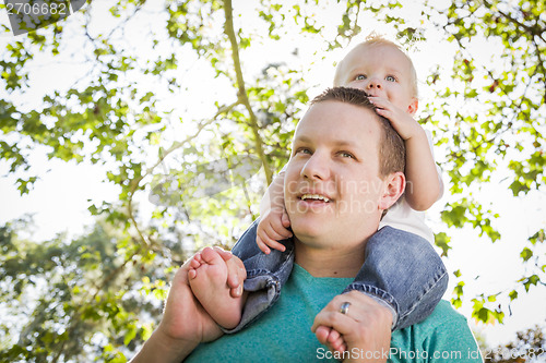 Image of Cute Young Boy Rides Piggyback On His Dads Shoulders