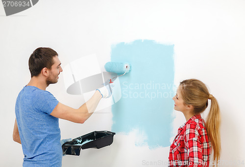 Image of smiling couple painting wall at home