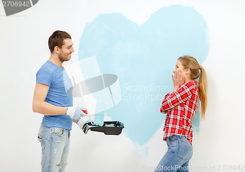 Image of smiling couple painting big heart on wall