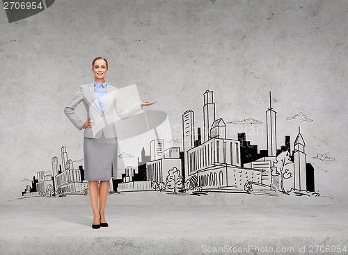 Image of smiling young businesswoman showing town sketch