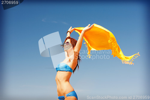 Image of happy woman with yellow sarong on the beach