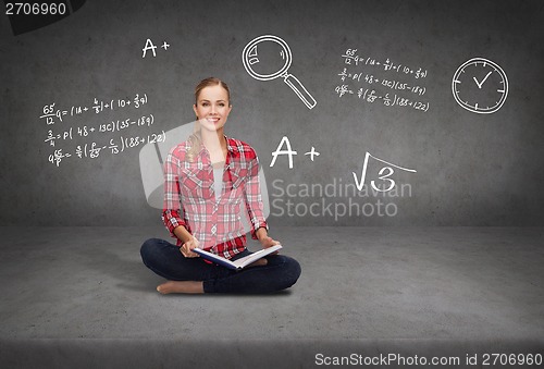 Image of smiling young woman sittin on floor with book