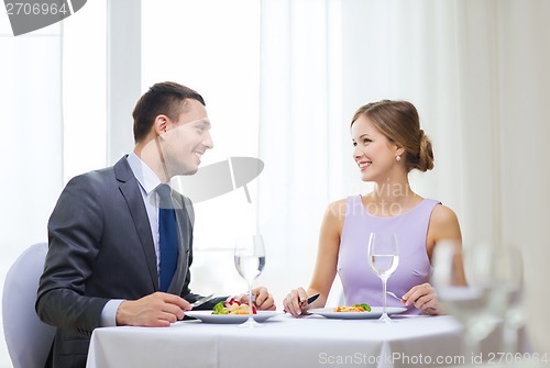 Image of smiling couple eating main course at restaurant