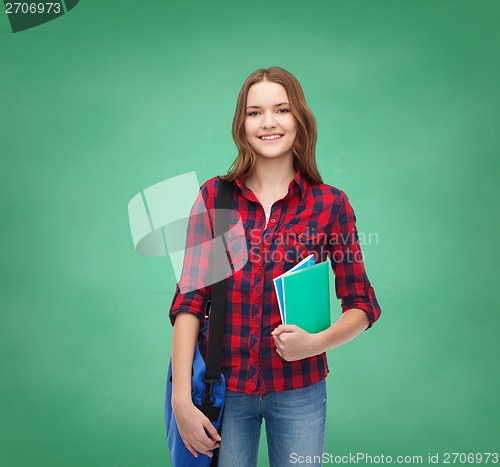 Image of smiling female student with bag and notebooks