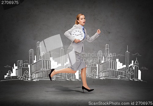 Image of stressed young businesswoman with clock running