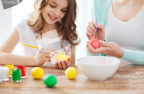 Image of close up of little girl and mother coloring eggs