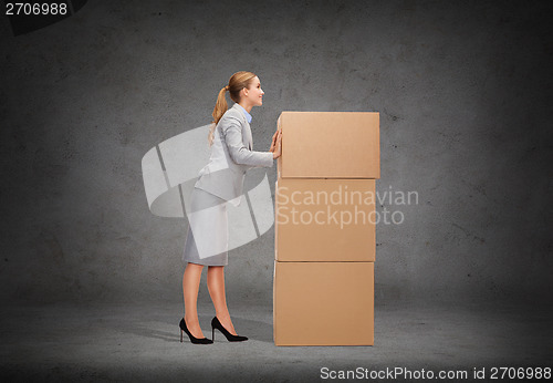 Image of smiling businesswoman pushing tower of cardboards