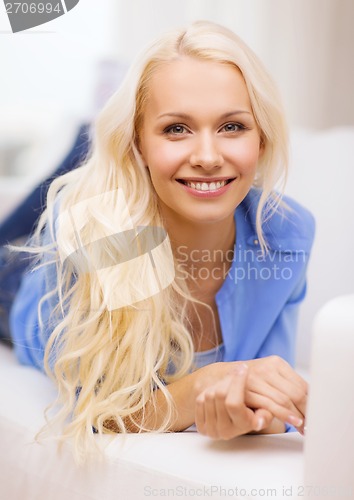 Image of smiling young woman lying on sofa at home