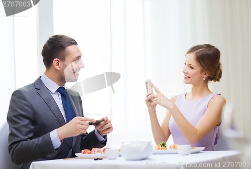 Image of smiling couple with sushi and smartphones