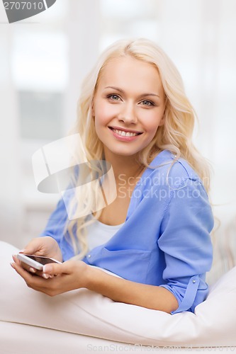 Image of smiling woman with smartphone at home