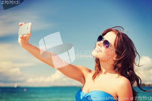 Image of happy woman with phone on the beach