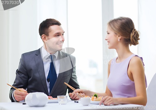 Image of smiling couple eating sushi at restaurant