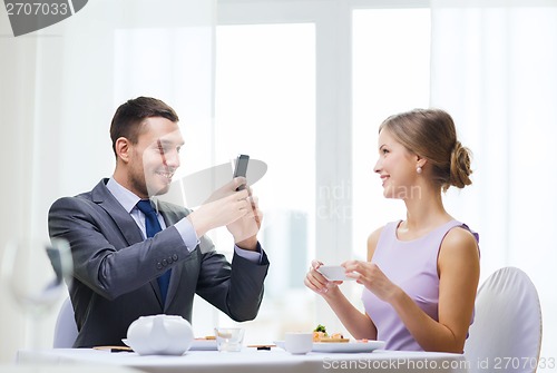 Image of smiling couple with sushi and smartphones
