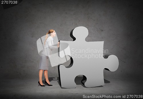 Image of smiling businesswoman pushing big puzzle piece