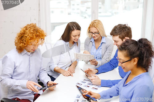 Image of smiling team with table pc and papers working