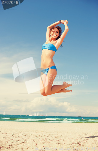 Image of happy jumping woman on the beach