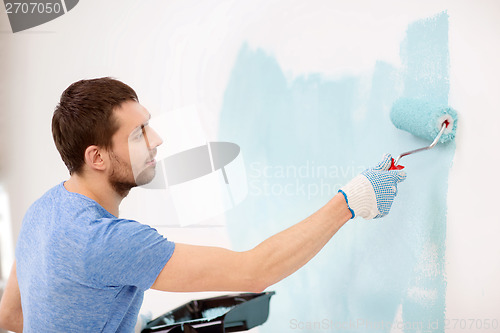 Image of smiling man painting wall at home