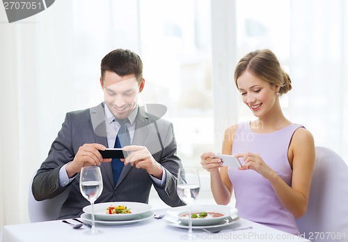 Image of smiling couple with appetizers and smartphones