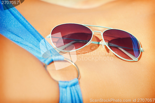 Image of female belly, bikini and shades