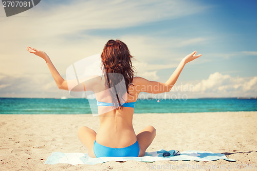 Image of woman practicing yoga lotus pose on the beach